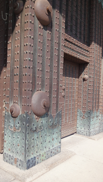 metal pillars support a metal door, both having rivets across their surfaces